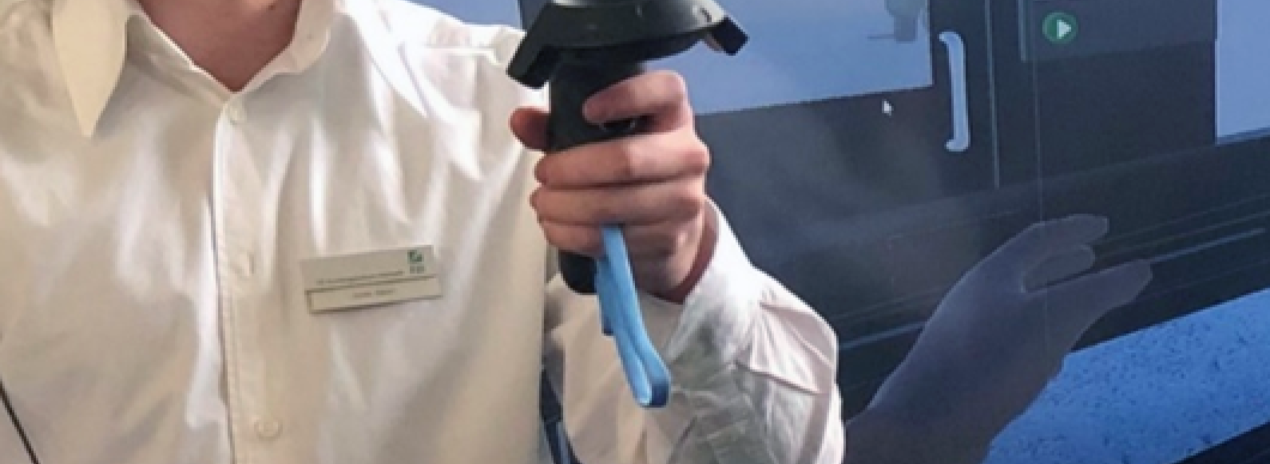Nutzer mit VR-Headset und Controllern vor einem Bildschirm, auf dem die VR-Umgebung zu sehen ist.