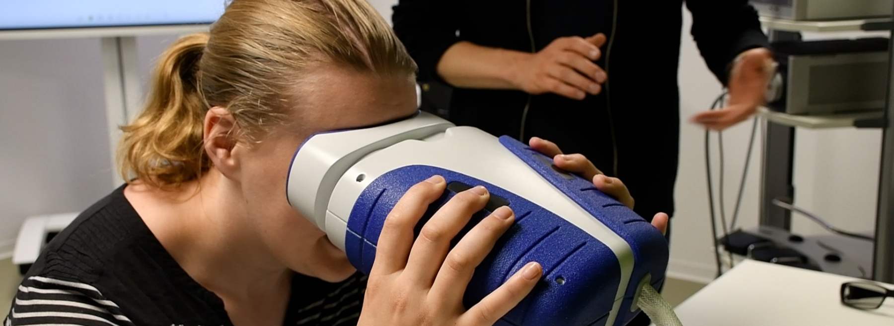 Eine Frau hält sich ein Gerät vor die Augen, das den Augenhintergrund aufnehmen kann