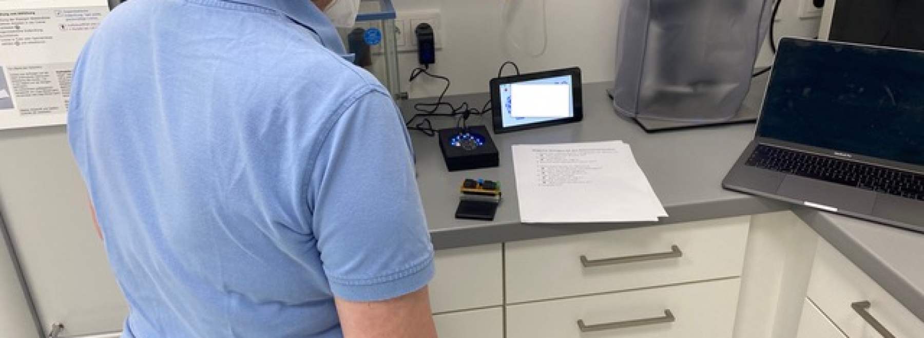 Das Bild zeigt eine Apothekenmitarbeiterin mit Mundschutz wie sie auf ein Tablet schaut.